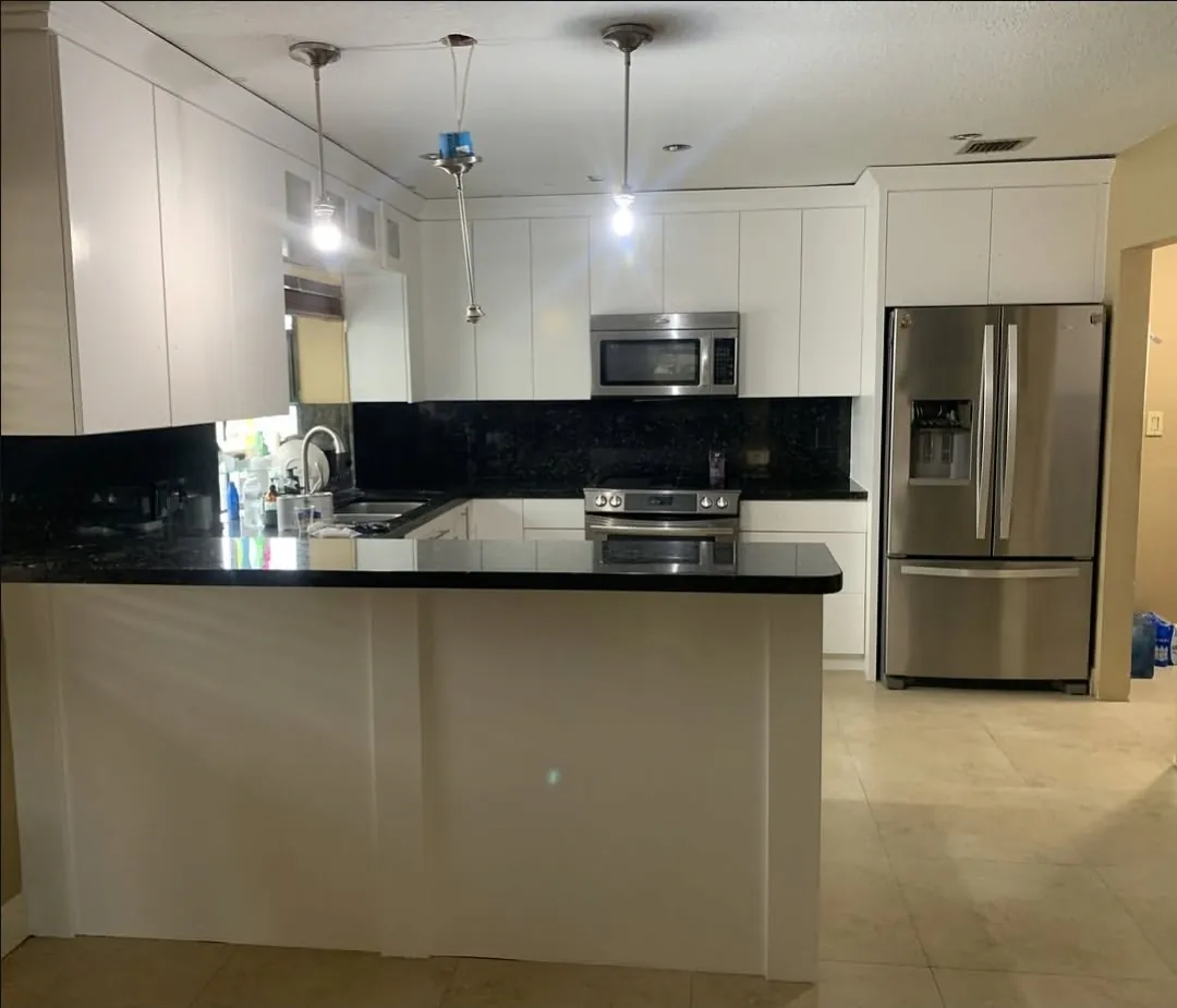 Kitchen after cabinet painting in white with black counters